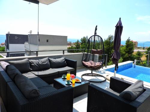 a patio with a couch and a swing and a pool at Villa Domus in Podstrana