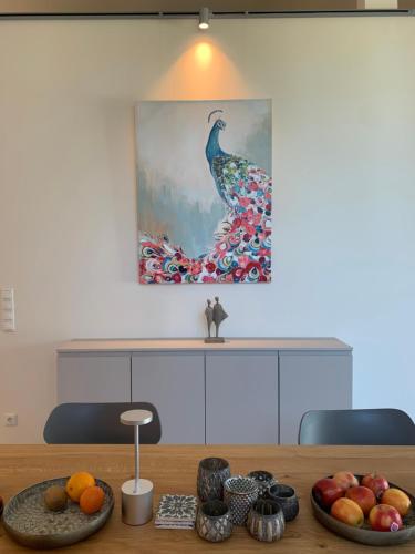 a painting of a peacock sitting on a table with fruit at Scheier (Ferienwohnungen) in Perl