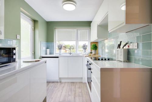 a kitchen with white cabinets and a large window at Lyndhurst Forest Edge - Sleeps 6 in Lyndhurst