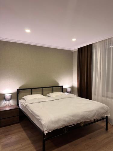 a bedroom with a bed with white sheets and two lamps at Woodland Borjomi in Borjomi