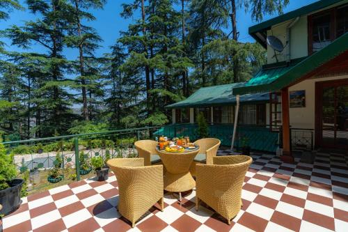 un patio con mesa y sillas en un suelo a cuadros en StayVista at Jai Cottage, en Shimla