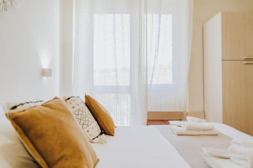 Un dormitorio con una cama blanca con almohadas y una ventana en Domus Cese, en Agrigento