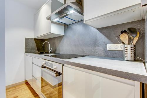 une cuisine avec des armoires blanches et un évier dans l'établissement Neige et Soleil 3eme, à Morzine