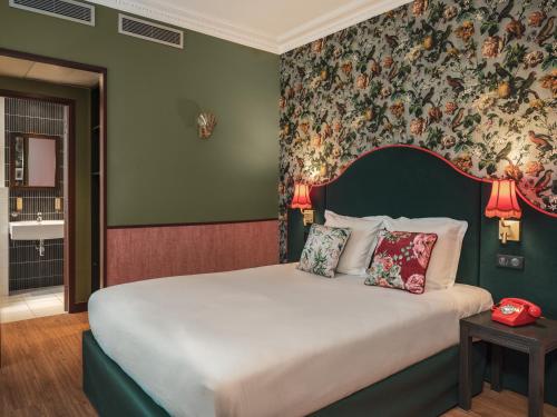 - une chambre avec un grand lit et du papier peint floral dans l'établissement Hôtel Brittany, à Paris