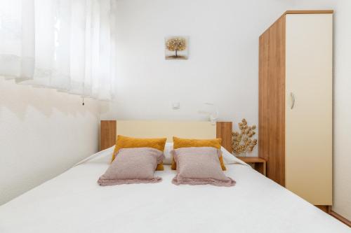 um quarto com uma cama branca e 2 almofadas em Relax Apartment Ive em Pula