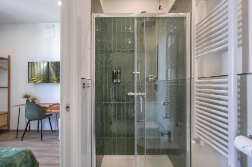 La salle de bains est pourvue d'une douche et d'une porte en verre. dans l'établissement VERSILIA MIA - beach at 8min by walk - new rooms!, à Viareggio