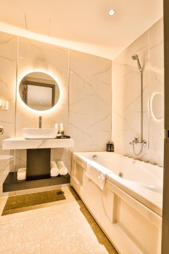 a white bathroom with a tub and a sink at La Paix Sài Gòn - Boutique Hotel in Ho Chi Minh City