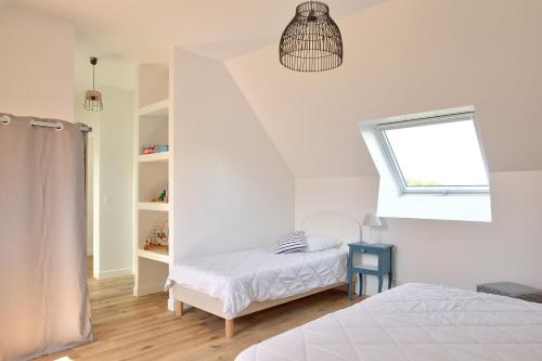 a white bedroom with a bed and a window at Vacances et détente en famille in Plovan
