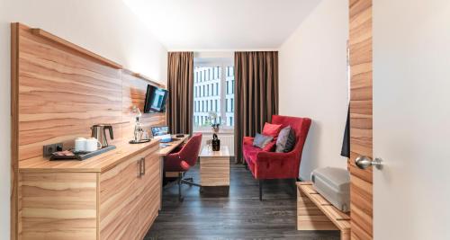 ein Hotelzimmer mit einem Schreibtisch und einem roten Stuhl in der Unterkunft PLAZA Premium Columbus Bremen in Bremen