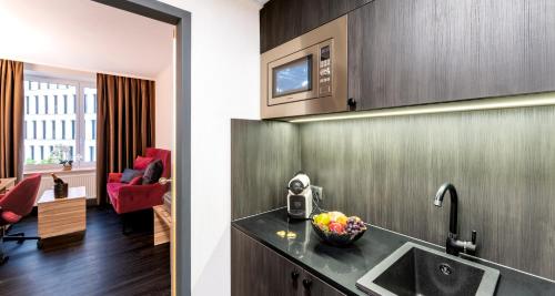 a kitchen with a sink and a living room at PLAZA Premium Columbus Bremen in Bremen