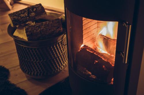 a fire in a fireplace with some bread in a basket at Scaldersitch Farm Boutique Glamping Tipi with private wood fired hot tub in Sheen