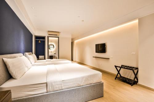a large bedroom with two beds and a television at La Paix Sài Gòn - Boutique Hotel in Ho Chi Minh City