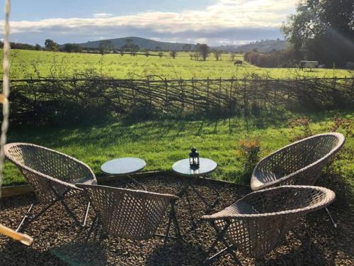 two chairs and a table with a surfboard in the grass at Scaldersitch Farm Boutique Glamping Tipi with private wood fired hot tub in Sheen