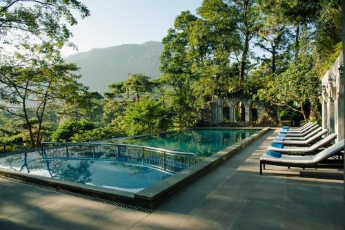 Melia Ba Vi Mountain Retreat في هانوي: مسبح في منتجع فيه كراسي واشجار
