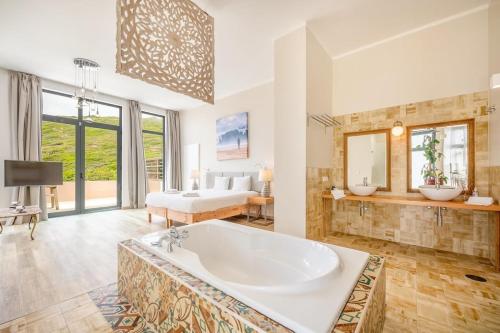 1 dormitorio y baño grande con bañera. en GuestReady - Luxury Beach Villa with Private Pool, en Ericeira