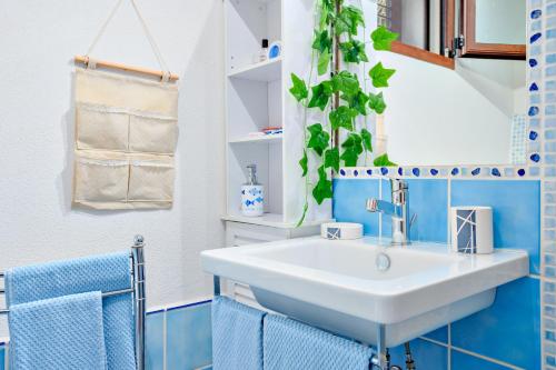 シニスコーラにあるAppartamento Caterinaの- 青いタイルのバスルーム(白いシンク付)