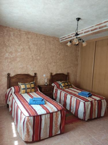 a bedroom with two beds and a ceiling at Casa Rural El Pajar Navaluenga in Navaluenga