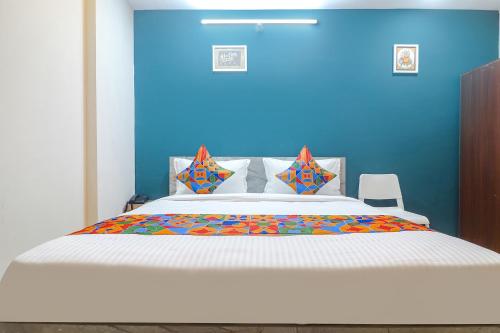 a bedroom with a large bed with a blue wall at FabHotel Broholic Suites I in Hyderabad