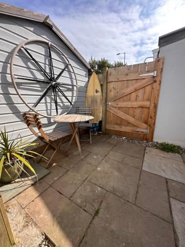 a patio with a wooden fence and a wooden wheel at Sea View Nook in Porthtowan