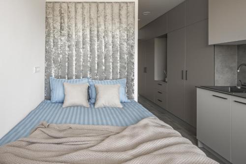 um quarto com uma cama grande e almofadas azuis em Mini-Home Apartamentai em Klaipėda