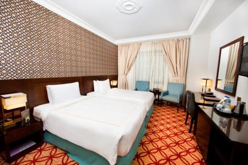 a hotel room with a large white bed and a desk at Dallah Taibah Hotel in Al Madinah