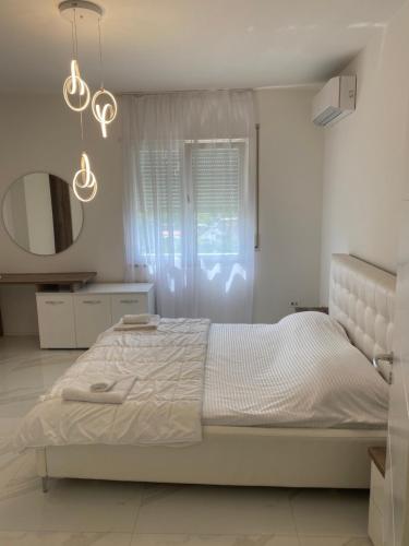 a white bedroom with a bed and a mirror at NÓS apartment 1 in Shkodër