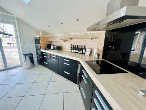 a kitchen with black cabinets and a stove top oven at "Villa du Circuit" avec Piscine, 4 Chambres, 4 SDB, à 8 min du circuit, parking et portail électrique in Mars-sur-Allier