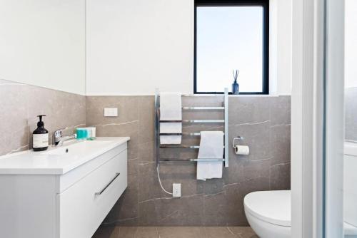 baño con lavabo y aseo y ventana en Stunning New 2BR Luxury in Pukekohe - WiFi Netflix en Pukekohe East