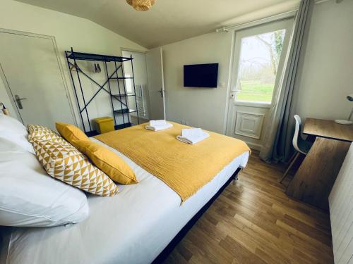 a bedroom with a bed with yellow pillows and a window at "Villa du Circuit" avec Piscine, 4 Chambres, 4 SDB, à 8 min du circuit, parking et portail électrique in Mars-sur-Allier