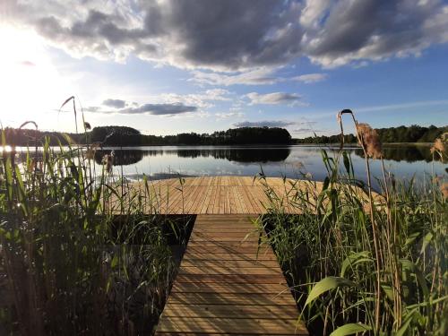 a dock on a body of water with the sun setting at Osada Wejsuny in Ruciane-Nida