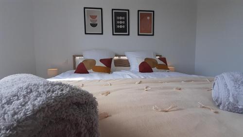 a bedroom with two white beds with pictures on the wall at La Bucolique in Simandre