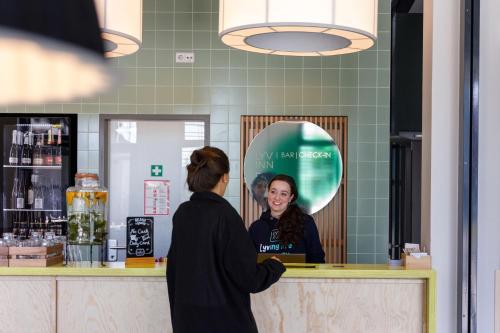 a woman standing at a counter talking to a customer at LyvInn Hotel Frankfurt Messe in Frankfurt