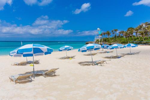 a group of chairs and umbrellas on a beach at 海まで徒歩1分 沖縄でも珍しい絶景ホテル 贅沢プライベートビーチ付き ビーチルーム in Onna