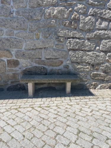 a bench sitting in front of a stone wall at Casa da Burra in Alijó
