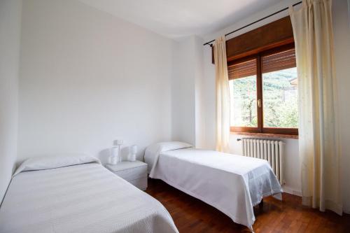 two beds in a white room with a window at Villa Diana - Appartamenti vista Lago in Brenzone sul Garda