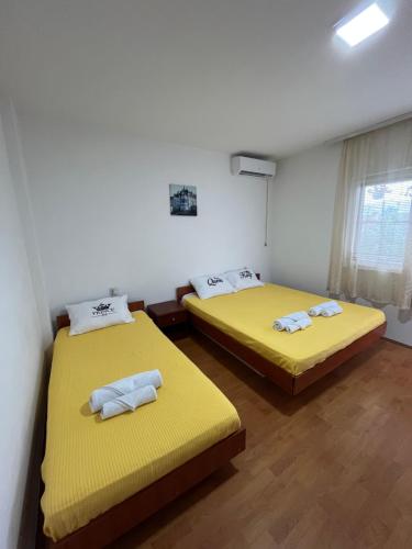 two beds in a room with yellow sheets at Villa Utopia in Star Dojran
