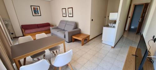 sala de estar con mesa, sillas y sofá en Apartamentos Laredo-Playa, en Laredo