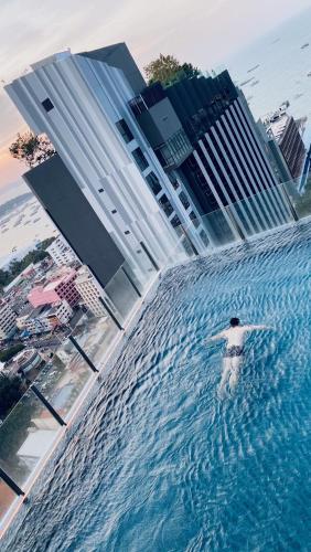 a person in a pool of water in front of buildings at BASE Central Pattaya King-Bed in Pattaya