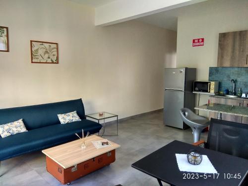 a living room with a blue couch and a refrigerator at APPARTMENT( LA PAPAYA) in La Gaulette