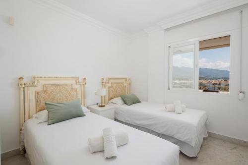 2 białe łóżka w białym pokoju z oknem w obiekcie Sea view apartment in the center of puerto Banús and private parking w Marbelli