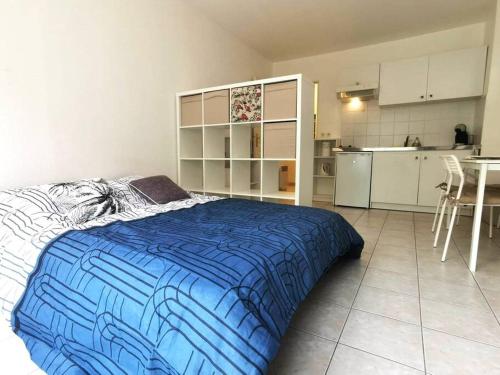 a bedroom with a blue bed and a kitchen at Studio Zen hypercentre parking privé WIFI in Salon-de-Provence