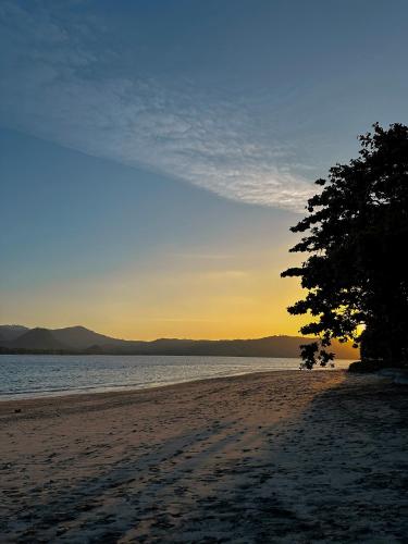 a beach with a tree and the ocean at sunset at Vayam Boutique Resort Gili Asahan in Gili Asahan
