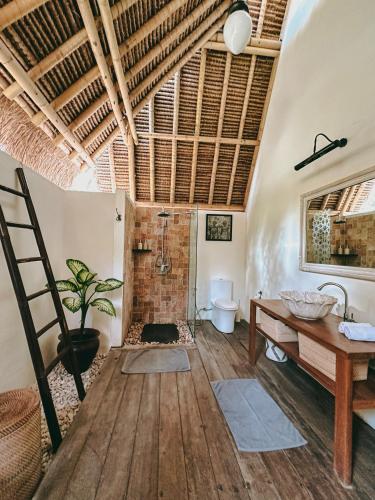 a bathroom with a sink and a toilet and a wooden floor at Vayam Boutique Resort Gili Asahan in Gili Asahan