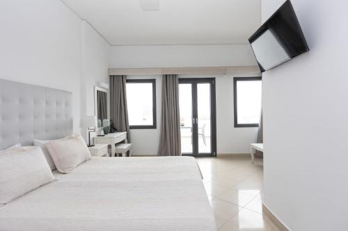 a white bedroom with a bed and a television at Hotel Star Santorini in Megalokhori