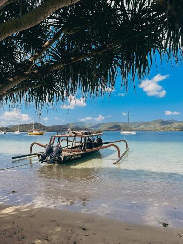 a boat sitting on the water on a beach at Vayam Boutique Resort Gili Asahan in Gili Asahan