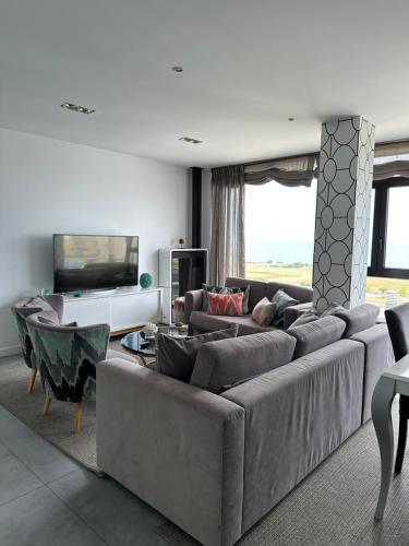 a living room with a large couch and a television at DÚPLEX DE LUJO EN FOZ CON VISTAS al MAR in Foz