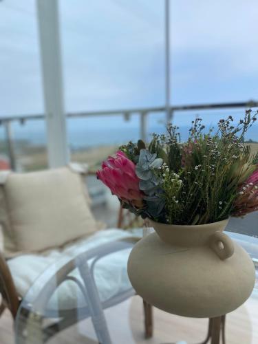 a vase of flowers sitting on a table with a chair at DÚPLEX DE LUJO EN FOZ CON VISTAS al MAR in Foz