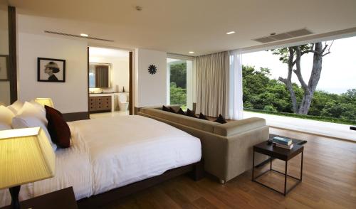 a bedroom with a bed and a couch and a window at Jirana Patong in Patong Beach
