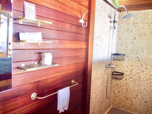 a bathroom with wooden walls and a shower with a sink at Le Karbé Bakov in Rémire-Camp