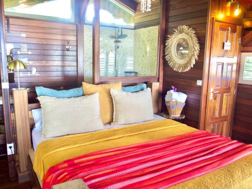 1 dormitorio con 1 cama con manta roja y amarilla en Le Karbé Bakov en Rémire-Camp